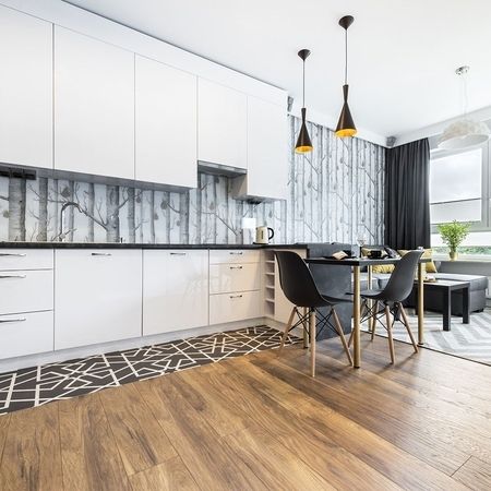 Eine moderne Küche mit weißen Schränken und Holzböden.