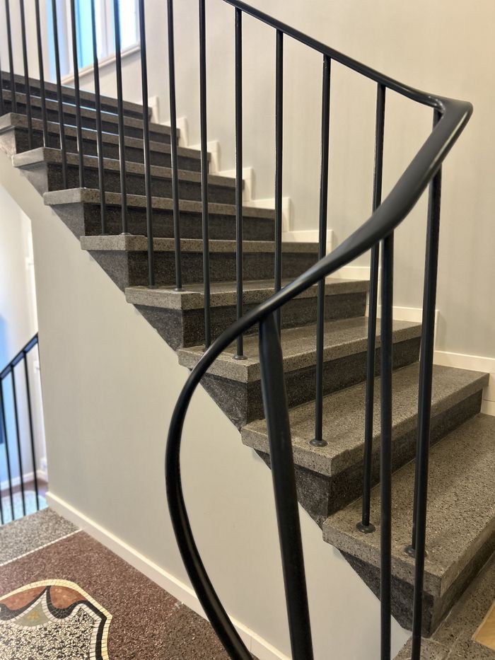 Eine Treppe mit schwarzen Geländern und einem Marmorboden.