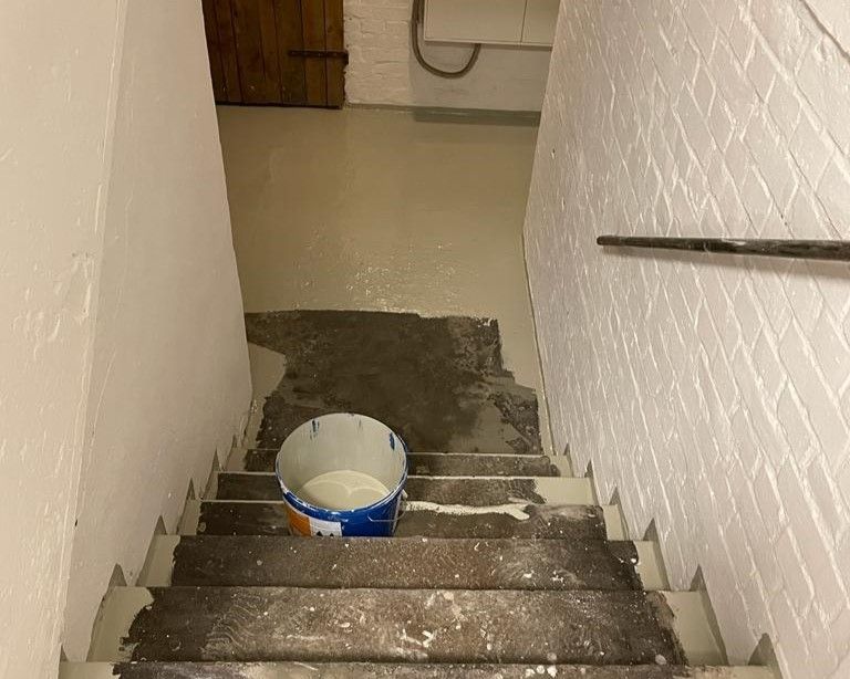Ein Eimer mit Zement steht auf der Treppe.