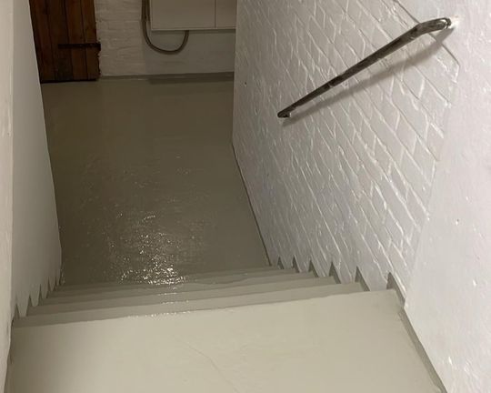 Eine Treppe mit einer weißen Wand und einem Handlauf.